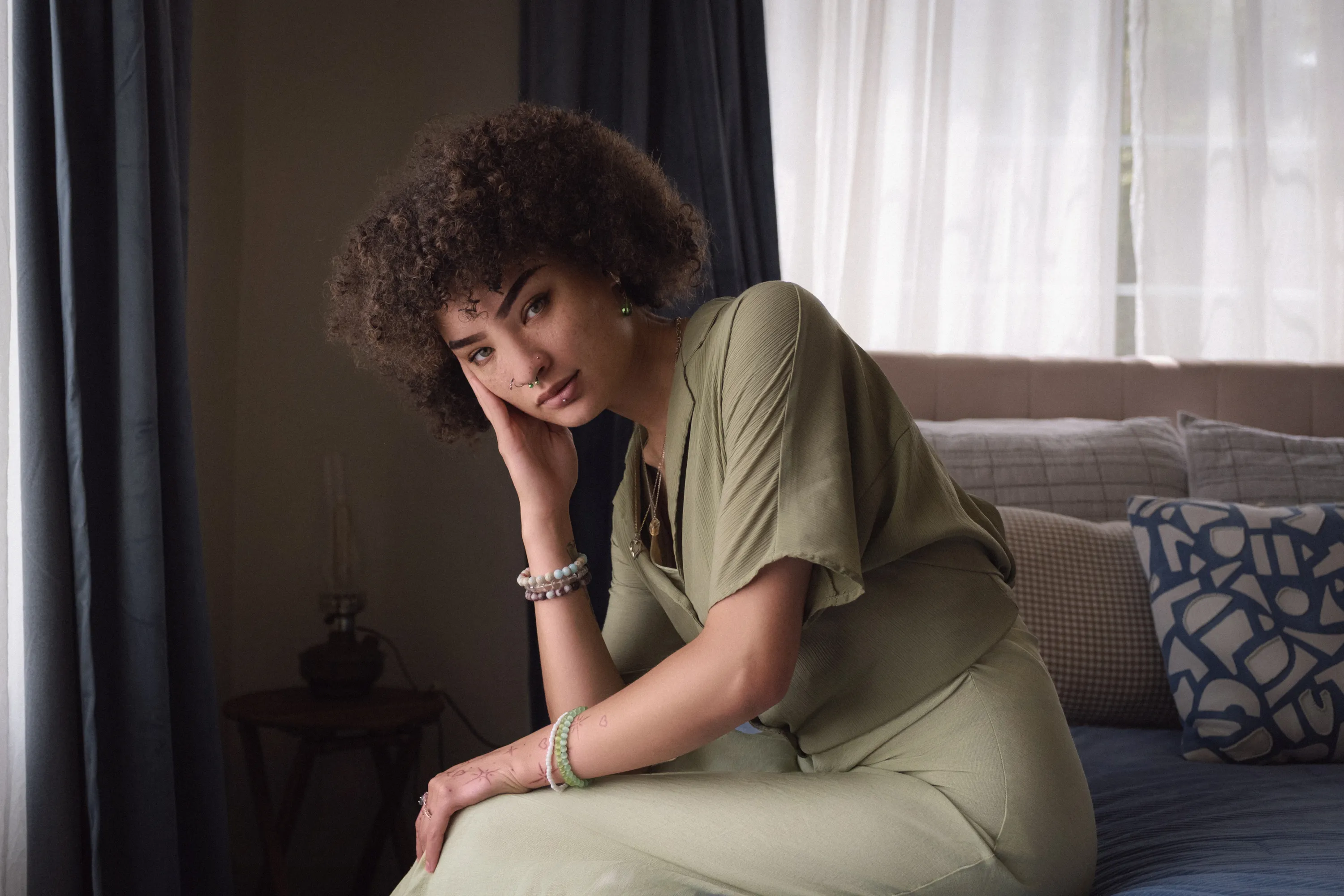 Relaxed indoor portrait seated beside a softly lit window